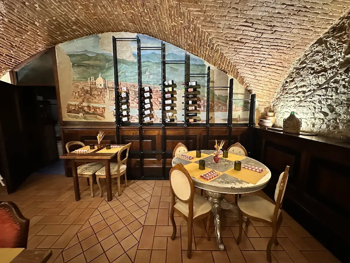 La saletta con l'affresco di Firenze sulla parete e le rastrelliere del vino davanti.