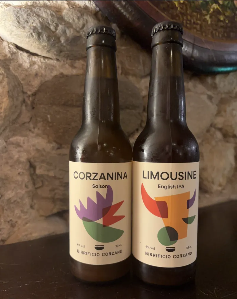 Le bottiglie Corzanina e Limousine del Birrificio Corzano appoggiate al muro di pietra.